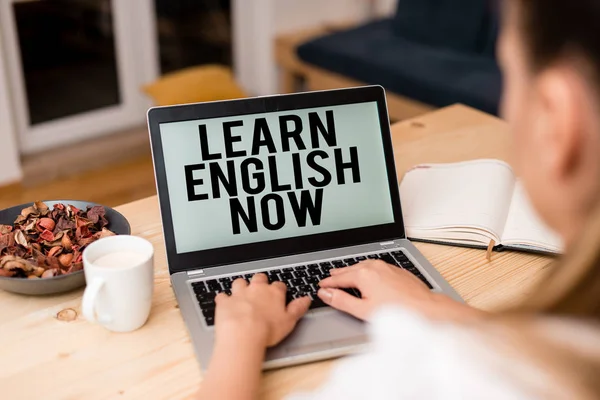 Handwriting text Learn English Now. Concept meaning gain or acquire knowledge and skill of english language woman laptop computer smartphone mug office supplies technological devices.