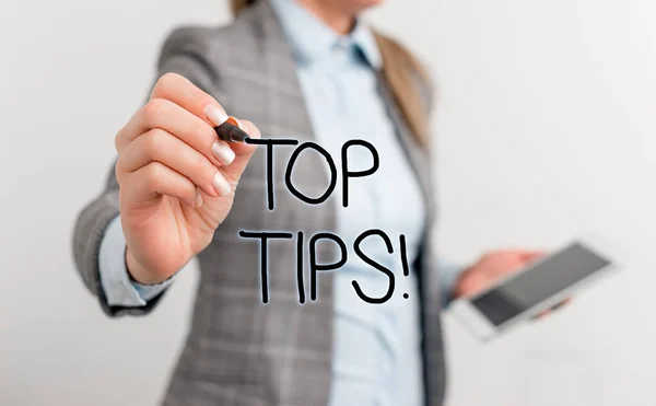 Text sign showing Top Tips. Conceptual photo small but particularly useful piece of practical advice Business woman pointing in empty space with pen and mobile phone.