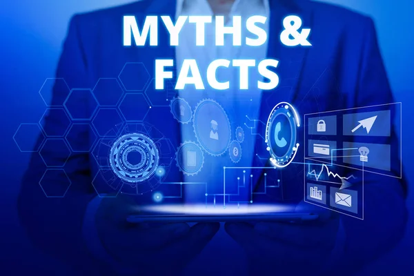 Text sign showing Myths And Facts. Conceptual photo usually traditional story of ostensibly historical events Male human wear formal work suit presenting presentation using smart device. — Stock Photo, Image