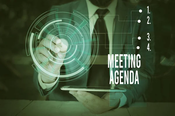 Writing note showing Meeting Agenda. Business photo showcasing items that participants hope to accomplish at a meeting Male wear formal suit presenting presentation smart device.