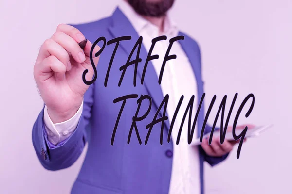 Text sign showing Staff Training. Conceptual photo program that helps employees learn specific knowledge Businessman in blue suite and white shirt pointing with finger in empty space.