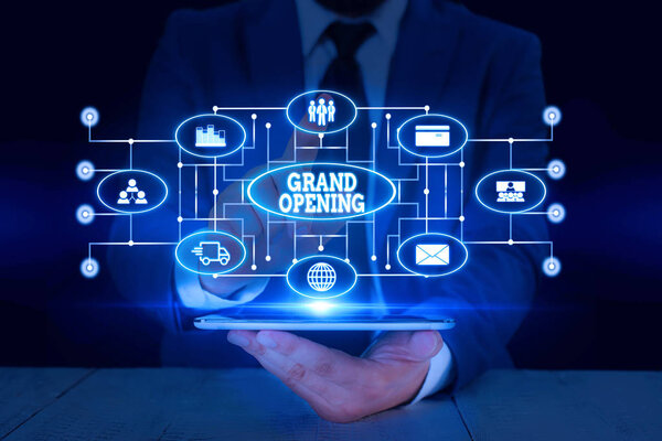 Text sign showing Grand Opening. Conceptual photo Ribbon Cutting New Business First Official Day Launching Male human wear formal work suit presenting presentation using smart device.