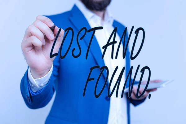 Text sign showing Lost And Found. Conceptual photo a place where lost items are stored until they reclaimed Businessman in blue suite and white shirt pointing with finger in empty space.