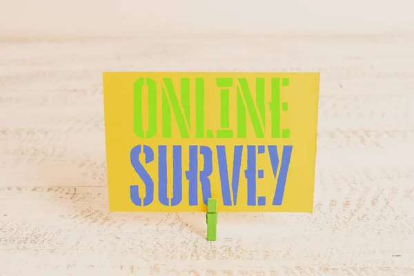 Text sign showing Online Survey. Conceptual photo Reappraisal Feedback Poll Satisfaction Rate Testimony Green clothespin white wood background colored paper reminder office supply.