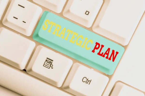 Text sign showing Strategic Plan. Conceptual photo a systematic process of envisioning a desired future White pc keyboard with empty note paper above white background key copy space.