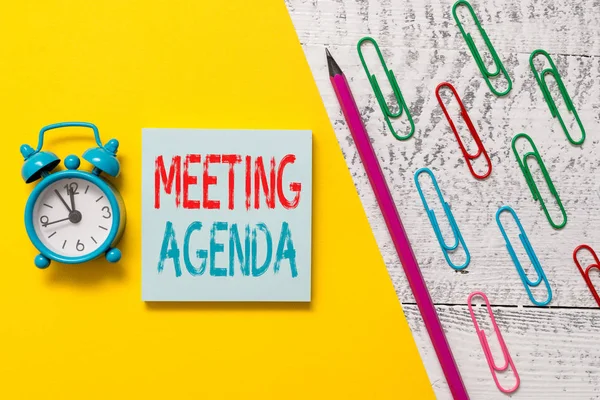 Handschrift Text Sitzung Tagesordnung. Konzept bedeutet, dass die Teilnehmer hoffen, bei einem Meeting Marker Stift farbige Büroklammern Wecker hölzernen Hintergrund zu erreichen. — Stockfoto