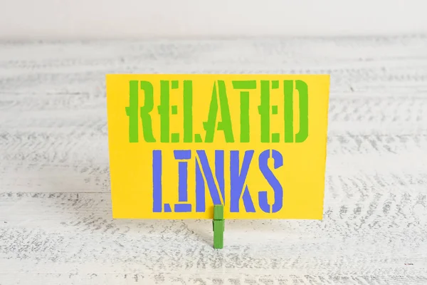 Text sign showing Related Links. Conceptual photo Website inside a Webpage Cross reference Hotlinks Hyperlinks Green clothespin white wood background colored paper reminder office supply.