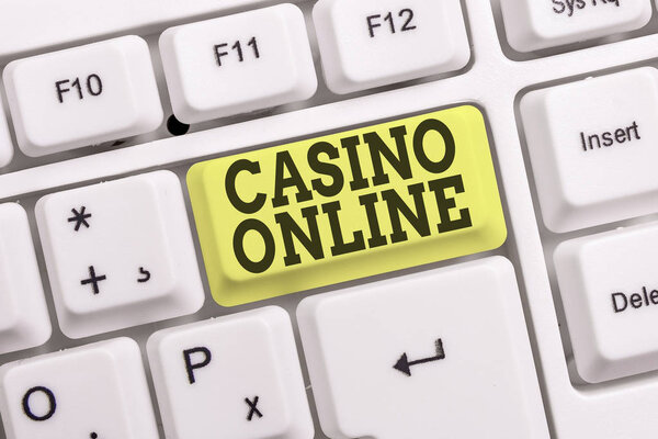 Conceptual hand writing showing Casino Online. Business photo text Computer Poker Game Gamble Royal Bet Lotto High Stakes White pc keyboard with note paper above the white background.