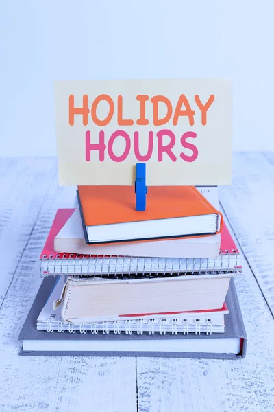 Fogalmi kézzel írásban mutatja Holiday hours. Üzleti fotó szöveg alkalmazottja kap kétszerese a normál fizetni minden órában halom halmozott könyvek notebook PIN színes emlékeztető fehér fából készült. — Stock Fotó