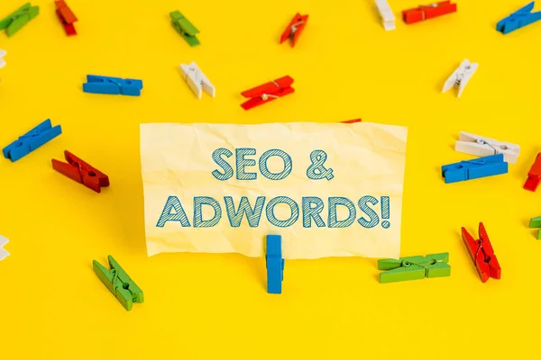 Seo Ve Adwords'u gösteren bir not yazıyorum. İş fotoğraf vitrin onlar Arama Motoru Pazarlama Renkli clothespin kağıtları boş hatırlatma sarı zemin arka plan ofis ana araçları bileşenleridir. — Stok fotoğraf