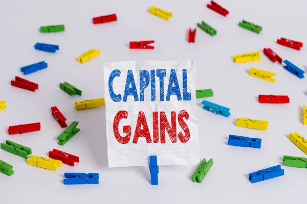 Text sign showing Capital Gains. Conceptual photo Bonds Shares Stocks Profit Income Tax Investment Funds Colored clothespin papers empty reminder white floor background office.