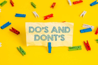 Bazı faaliyet veya eylemlerle ilgili Kurallar veya gelenekleri sergileyen Do And Dont S. Business fotoğrafını gösteren not yazma Renkli clothespin kağıtları boş hatırlatma sarı zemin arka plan ofis.