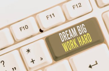 Dream Big Work Hard'ı gösteren bir not yazıyorum. İş fotoğraf vitrin kendinize inanın ve beyaz arka plan üzerinde not kağıdı ile hayalleri ve hedefleri beyaz pc klavye izleyin.