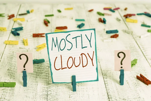 Conceptual hand writing showing Mostly Cloudy. Business photo showcasing Shadowy Vaporous Foggy Fluffy Nebulous Clouds Skyscape Crumbling sheet with paper clips placed on the wooden table. — Stock Photo, Image