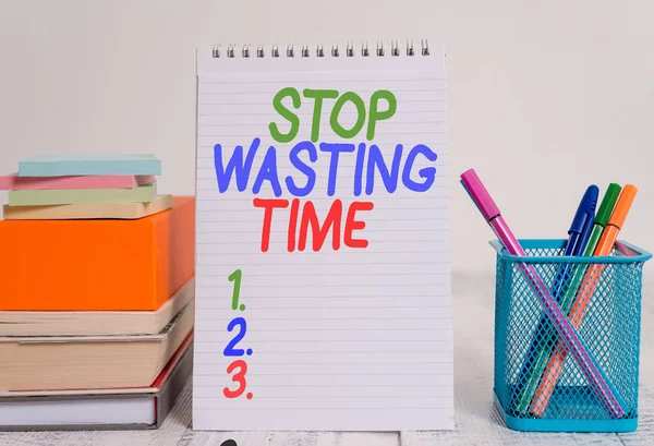 Text sign showing Stop Wasting Time. Conceptual photo advising demonstrating or group start planning and use it wisely Pens metal holder stacked note pads books square box spiral wooden table. — Stock Fotó