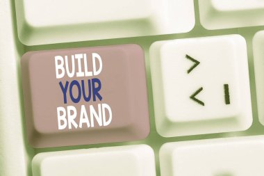 Markanızı Oluştur'da yazılı el yazısı metin. Kavram reklam kampanyaları kullanarak marka eşitliğini artırma Beyaz pc klavye beyaz arka plan anahtar kopyalama alanı üzerinde boş not kağıdı ile.