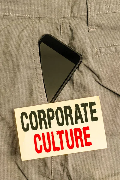 Word writing text Corporate Culture. Business concept for pervasive values and attitudes that characterize a company Smartphone device inside formal work trousers front pocket near note paper.