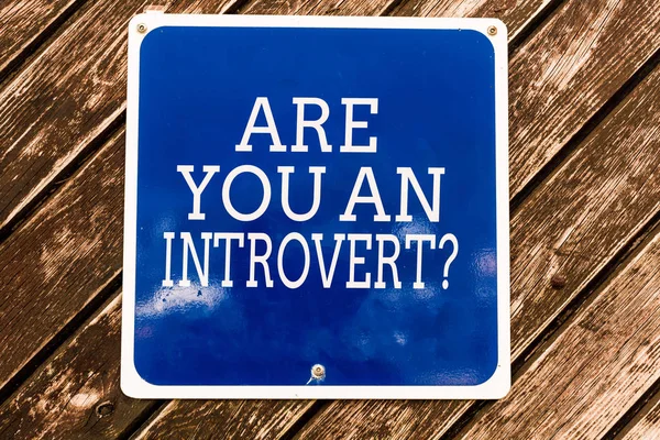 Handwriting text writing Are You An Introvertquestion. Concept meaning demonstrating who tends to turn inward mentally Empty blue board with copy space above wooden background. — Stock Photo, Image