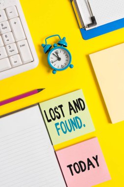 Kayıp Ve Bulun'u gösteren kavramsal el yazısı. İş fotoğrafı metni, masa saati mobil ve pc klavyesi üzerindeki buruşuk beyaz kağıdı geri alana kadar kayıp öğelerin depolandığı bir yer.