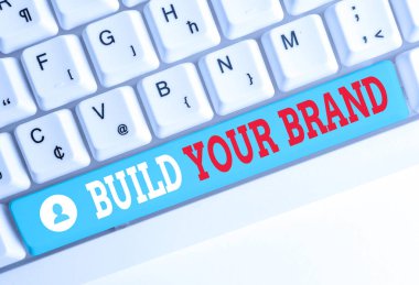 Kelime yazma metni Markanızı Oluşturun. Reklam kampanyaları kullanarak marka eşitliğini artırmak için iş konsepti Beyaz pc klavye beyaz arka plan anahtar kopyalama alanı üzerinde boş not kağıdı ile.