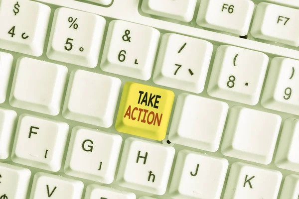 Writing note showing Take Action. Business photo showcasing to do somethingoract in order to get a particular result White pc keyboard with note paper above the white background.