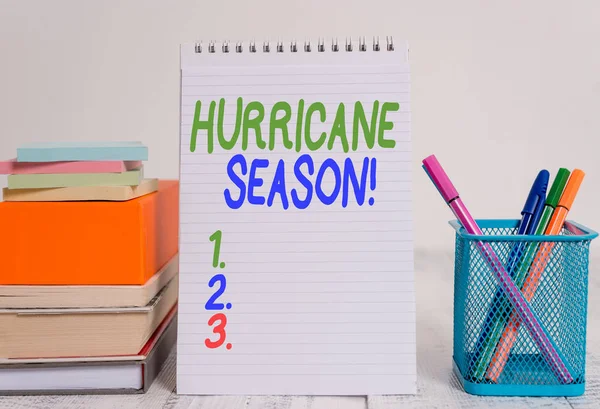 Text sign showing Hurricane Season. Conceptual photo time when most tropical cyclones are expected to develop Pens metal holder stacked note pads books square box spiral wooden table.