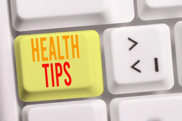 Handwriting text writing Health Tips. Concept meaning advice or information given to be helpful in being healthy White pc keyboard with empty note paper above white background key copy space.