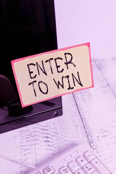 Текст для записи слов Enter To Win. Бизнес-концепция обмена чего-то ценного на приз или шанс выиграть Нота-бумага, прикрепленная к черному экрану монитора компьютера рядом с белой клавиатурой . — стоковое фото