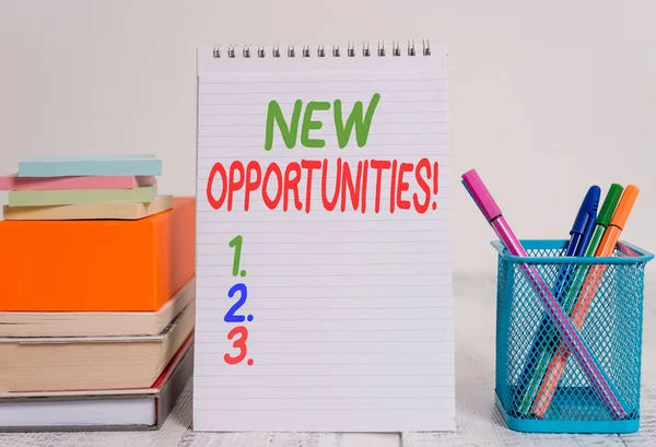 Text sign showing New Opportunities. Conceptual photo exchange views condition favorable for attainment goal Pens metal holder stacked note pads books square box spiral wooden table.