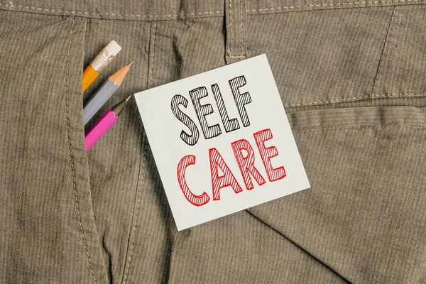 Handwriting text Self Care. Concept meaning the practice of taking action to improve one s is own health Writing equipment and blue note paper inside pocket of man work trousers. — Stock Photo, Image
