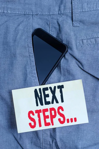 Word writing text Next Steps. Business concept for something you do or plan after you ve finished something else Smartphone device inside formal work trousers front pocket near note paper.