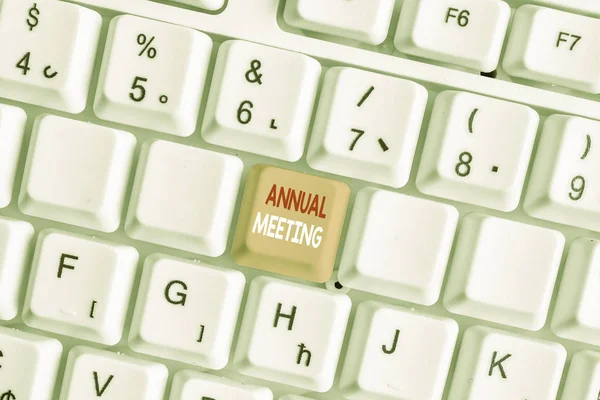 Writing note showing Annual Meeting. Business photo showcasing yearly meeting of the general membership of an organization White pc keyboard with note paper above the white background.