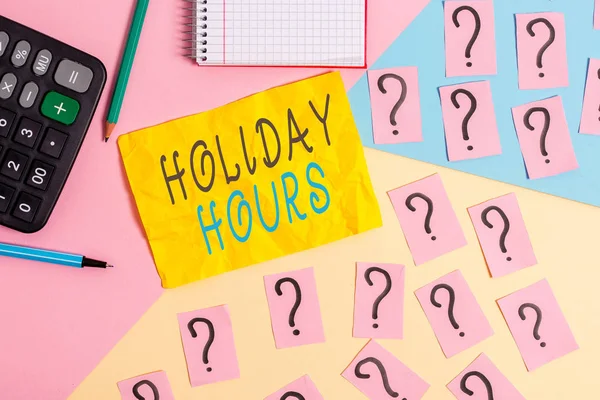 Notat som viser "Holiday Hours". Forretningsfoto-ansatte får dobbel lønn for all timevis matematikk og skrivesaker over pastellfarget bakgrunn. . – stockfoto