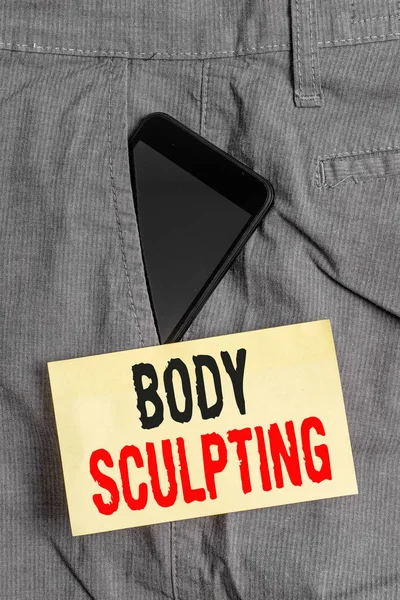 Word writing text Body Sculpting. Business concept for activity of increasing the body s is visible muscle tone Smartphone device inside formal work trousers front pocket near note paper.