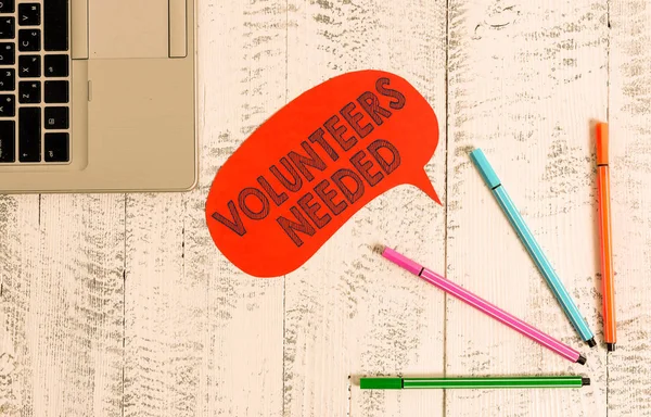 Escribir texto a mano Se necesitan voluntarios. Concepto que significa necesidad de trabajo o ayuda para la organización sin ser pagado Portátil abierto bolígrafos de burbuja discurso en blanco acostado mesa de madera vintage . — Foto de Stock