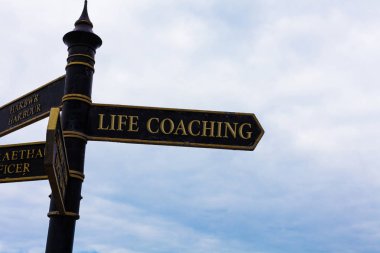 Text sign showing Life Coaching. Conceptual photo Improve Lives by Challenges Encourages us in our Careers Road sign on the crossroads with blue cloudy sky in the background. clipart