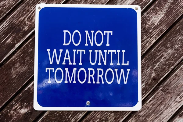 Handwriting text writing Do Not Wait Until Tomorrow. Concept meaning needed to do it right away Urgent Better do now Empty blue board with copy space above wooden background.
