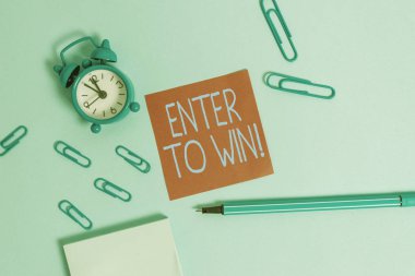 Enter To Win'i gösteren kavramsal el yazısı. Ödül kazanma ödülü için bir değer alışverişi gösteren Iş fotoğraf Çalar saat not defteri yapışkan not kalemi renkli arka plan.