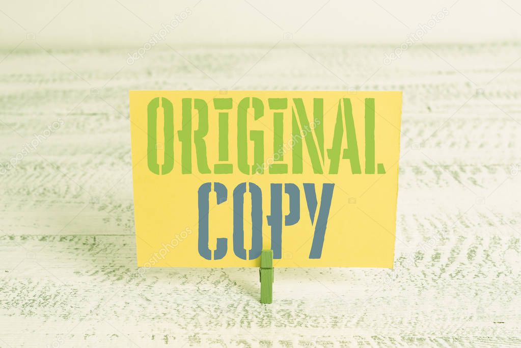 Text sign showing Original Copy. Conceptual photo Main Script Unprinted Branded Patented Master List Green clothespin white wood background colored paper reminder office supply.