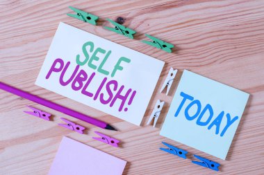 El yazısı metin Self Publish. Kavram anlamı yazar kendi pahasına bağımsız çalışma parçası yayınlamak Renkli clothespin kağıtları boş hatırlatma ahşap zemin arka plan ofis.