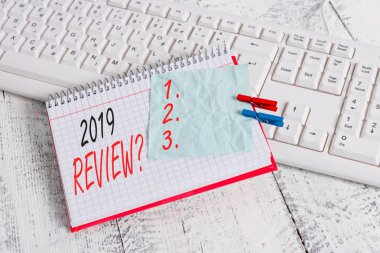 2019 Gözden Geçirme Sorusunu gösteren metin işareti. Kavramsal fotoğraf geçen yıl olaylar ana eylemleri veya iyi hatırlayarak defter kağıt hatırlatma clothespin iğneli levha beyaz klavye ışık ahşap gösterir.