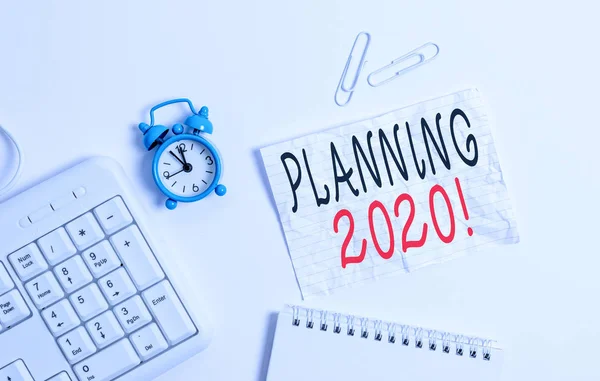Zapisuje se Poznámka o plánování 2020. Proces tvorby fotografií v zaměstnání v příštím roce je prázdný papír s prostorem pro kopírování v tabulce s hodinami a klávesnicí PC. — Stock fotografie