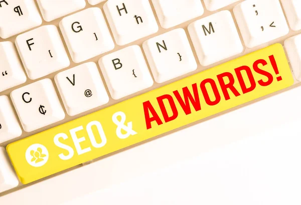 Word szöveget írni SEO és az AdWords. Üzleti koncepció azok fő eszköze összetevői Search Engine Marketing fehér PC billentyűzet üres jegyzet papír felett fehér háttér-kulcs másolata hely. — Stock Fotó