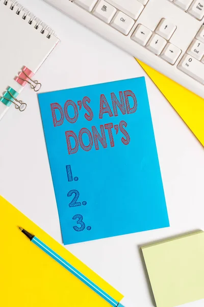 Conceptual hand writing showing Do S And Dont S. Business photo text Rules or customs concerning some activity or actions Colored paper binder clip sheets white desk empty space. — Stock Photo, Image