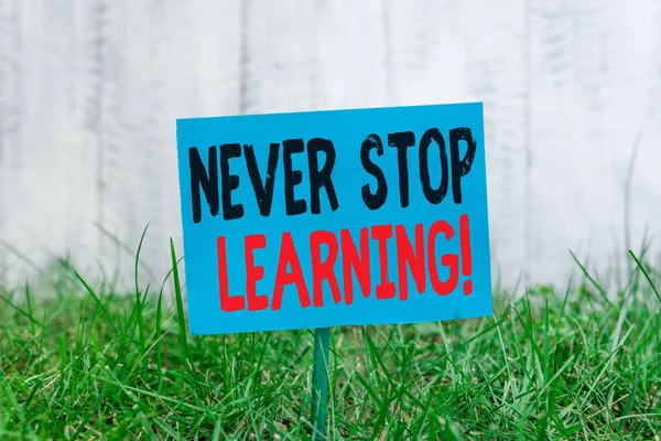 Handwriting text Never Stop Learning. Concept meaning keep on studying gaining new knowledge or materials Plain empty paper attached to a stick and placed in the green grassy land.