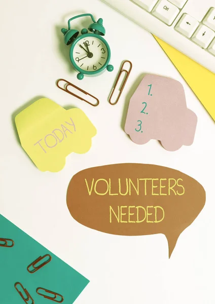Word writing text Volunteers Needed. Business concept for need work or help for organization without being paid Flat lay with copy space on bubble paper clock and paper clips.