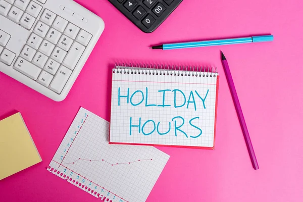 Sana kirjoittaa tekstiä Holiday Hours. Työntekijän liiketoimintakonsepti saa kaksinkertaisen normaalin palkan kaikista tunneista Kirjoitusvälineet ja tietokoneet sijoitettu klassisen puupöydän päälle . — kuvapankkivalokuva