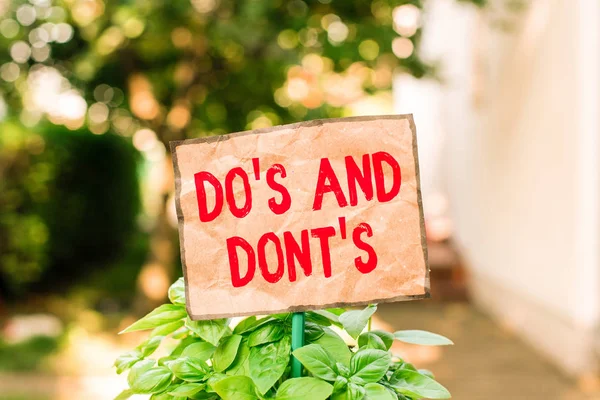 Schreiben Notiz zeigt do s und dont s. Business-Foto zeigt Regeln oder Bräuche in Bezug auf einige Aktivitäten oder Aktionen Normalpapier am Stick befestigt und in der Wiese platziert. — Stockfoto