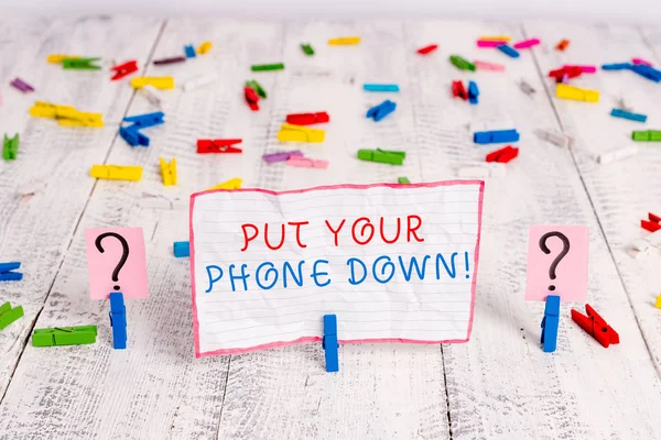 Handwriting text writing Put Your Phone Down. Concept meaning end telephone connection saying goodbye caller Scribbled and crumbling sheet with paper clips placed on the wooden table.
