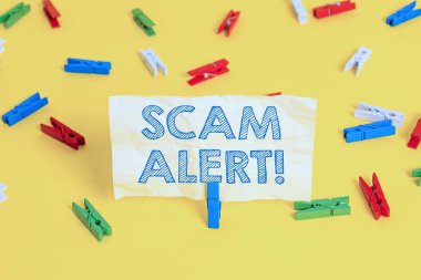 Scam Alert'i gösteren not yazma. İş fotoğraf vitrin hileli onu Renkli clothespin kağıtları boş hatırlatma sarı zemin arka plan ofis ikna ederek kurbandan para elde.